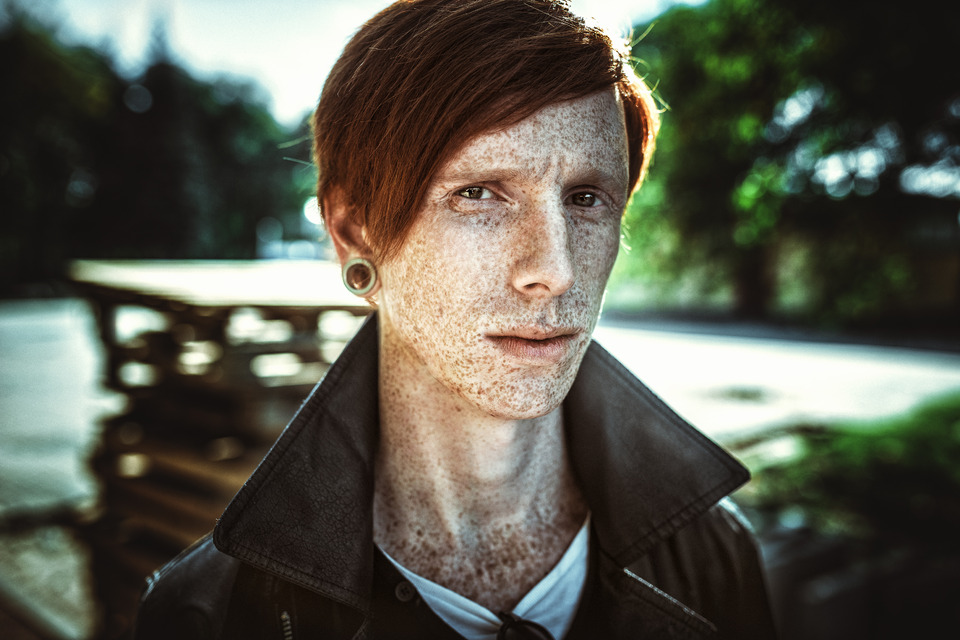 Freckled redhead man with ear tunnels | ear tunnel, freckled model, redhead man, environmental portrait, trees, light